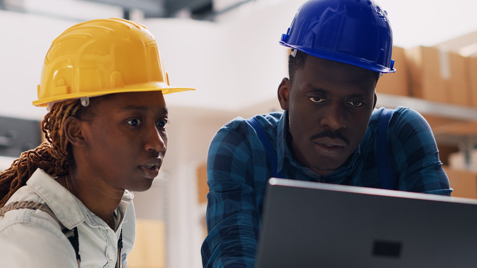 Two young people in overalls working in warehouse